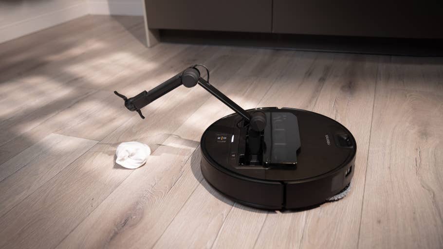A Roborock Saros Z70 robot vacuum cleaner on a wooden floor next to a cloth.