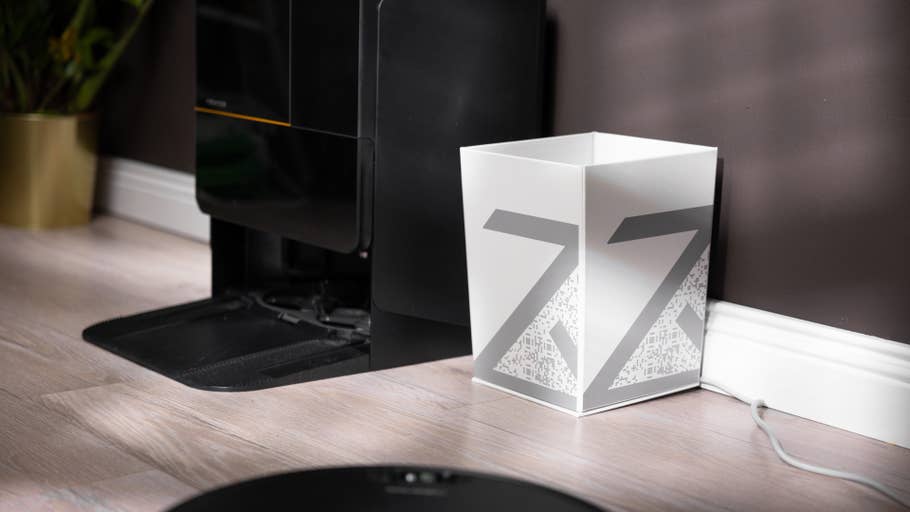 A Roborock docking station next to a white bin with a gray design showing the letter Z.