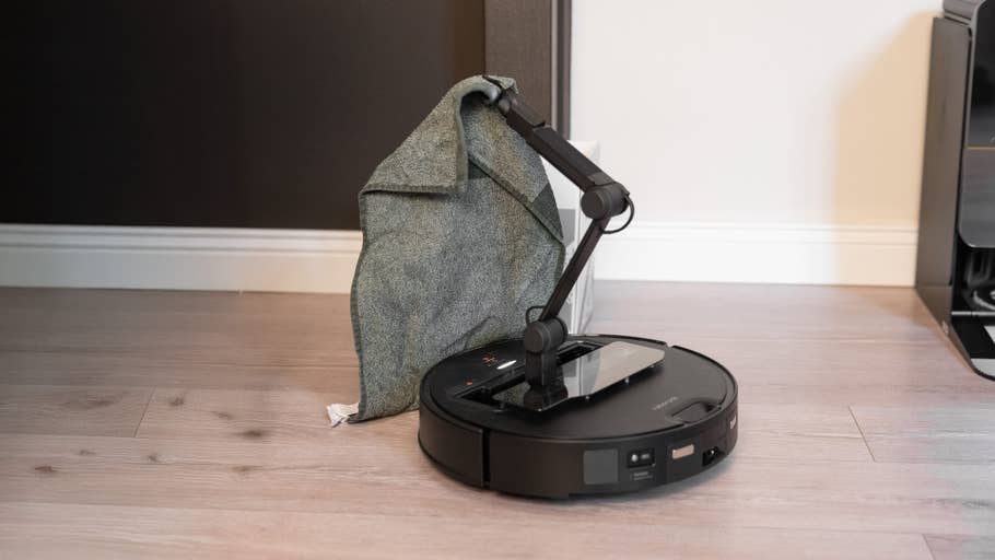 A Roborock Saros Z70 with a grey cloth lying over it on a wooden floor.