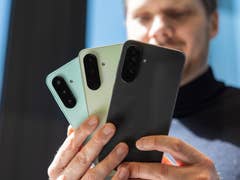 A person holding three Samsung Galaxy A series smartphones in different colors.