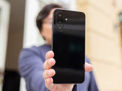 A person holding a Samsung Galaxy A26 smartphone, displaying its sleek black back.