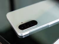 A Samsung Galaxy A56 smartphone lies on a glass surface and shows its camera module and design.