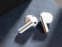Samsung Galaxy Buds 3 resting on a dark surface, showcasing their sleek white design.