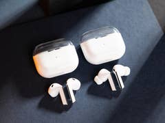 Two pairs of Samsung Galaxy Buds 3 wireless earbuds with their charging cases on a dark surface.