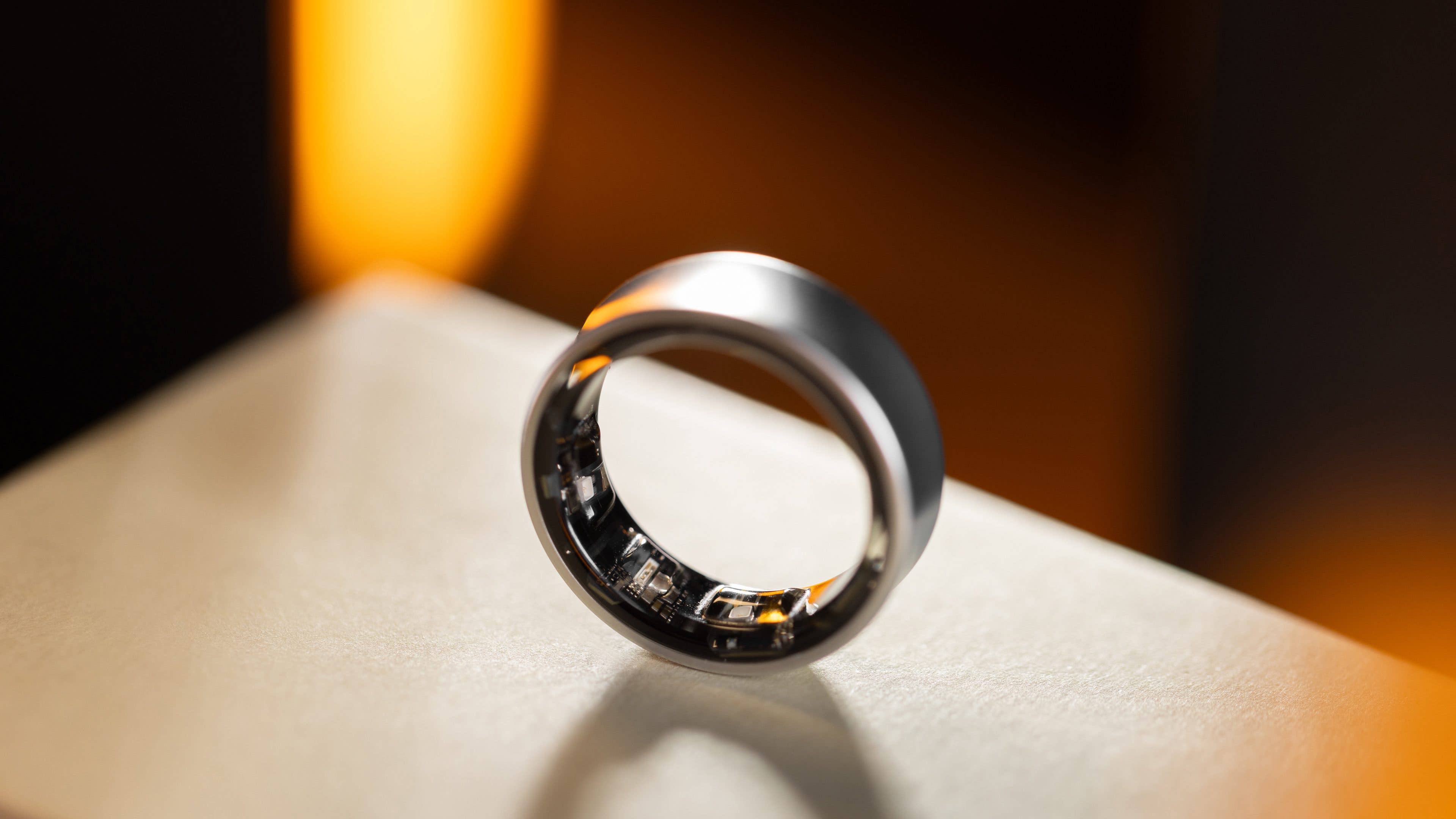 A sleek Samsung Galaxy Ring displayed on a surface with a soft light background. A sleek Samsung Galaxy Ring displayed on a surface with a soft light background.