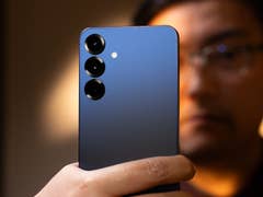 A person holding a Samsung Galaxy S25 Plus smartphone with a blue gradient back and three camera lenses.