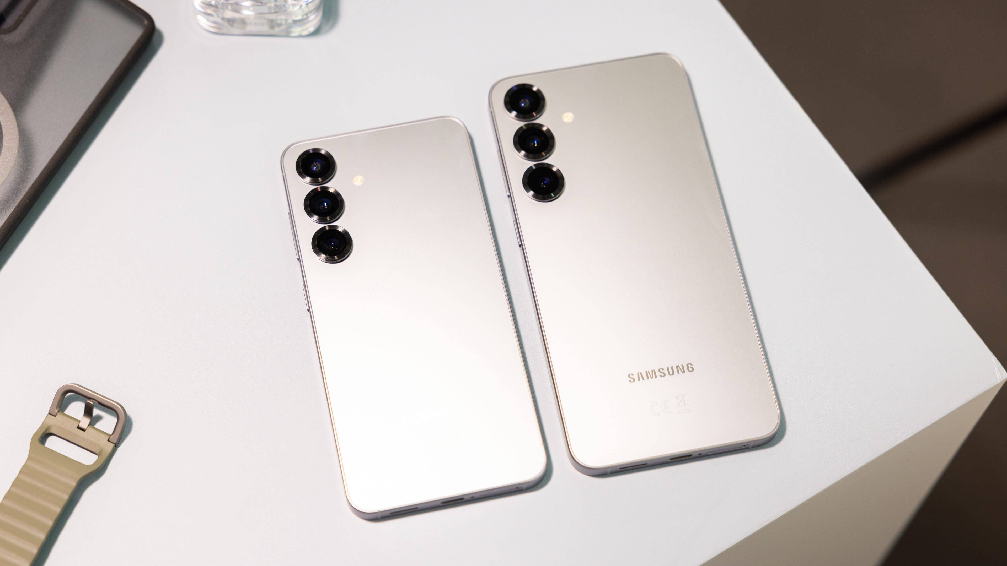 Two Samsung Galaxy S25 smartphones on a table, facing back, showcasing their camera designs.