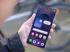 A person holding a Samsung Galaxy S25 Ultra smartphone displaying weather information and app icons.