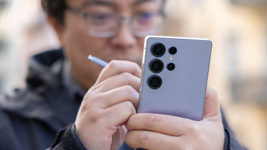 A person holding a Samsung Galaxy S25 Ultra smartphone with a stylus, focusing on the deviceu0027s camera.