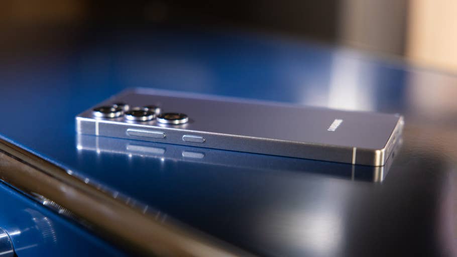 A Samsung Galaxy S25 Ultra smartphone resting on a reflective blue surface.