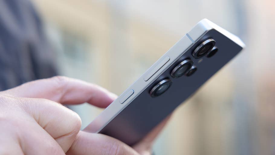 A close-up of a personu0027s hand holding a Samsung Galaxy S25 Ultra smartphone from the side.