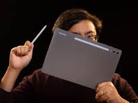 Person holding a Samsung Galaxy Tab S10+ and stylus against a dark background.