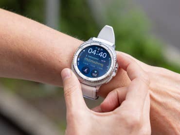 A person using a Samsung Galaxy Watch 8 Classic on their wrist, displaying time and fitness stats.