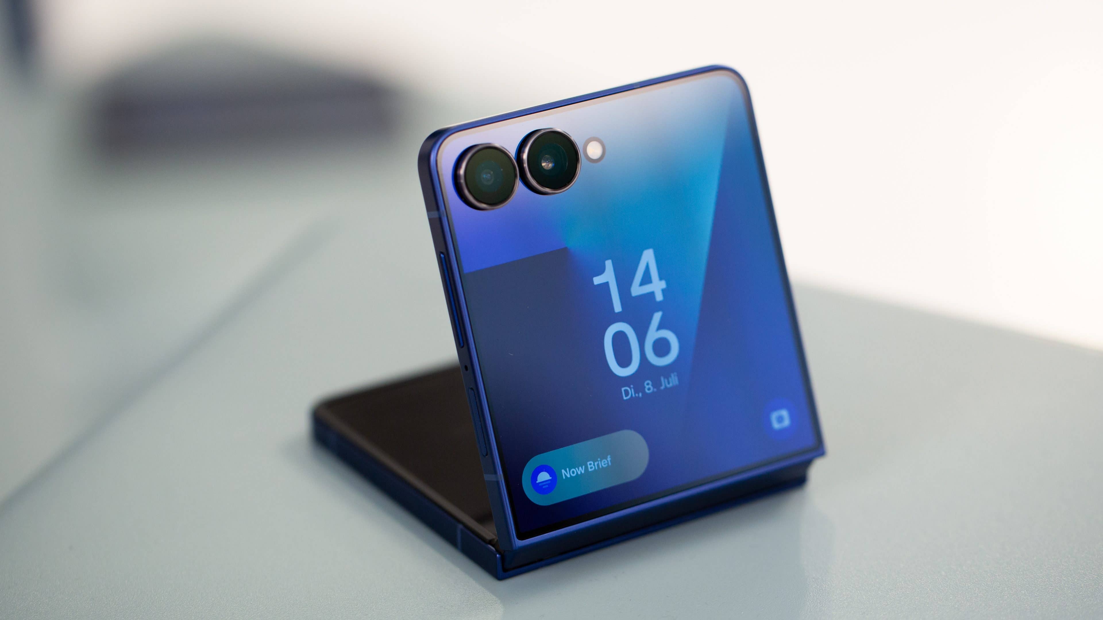Samsung Galaxy Z Flip7 smartphone displayed at an angle with a blue design and clock on the screen.