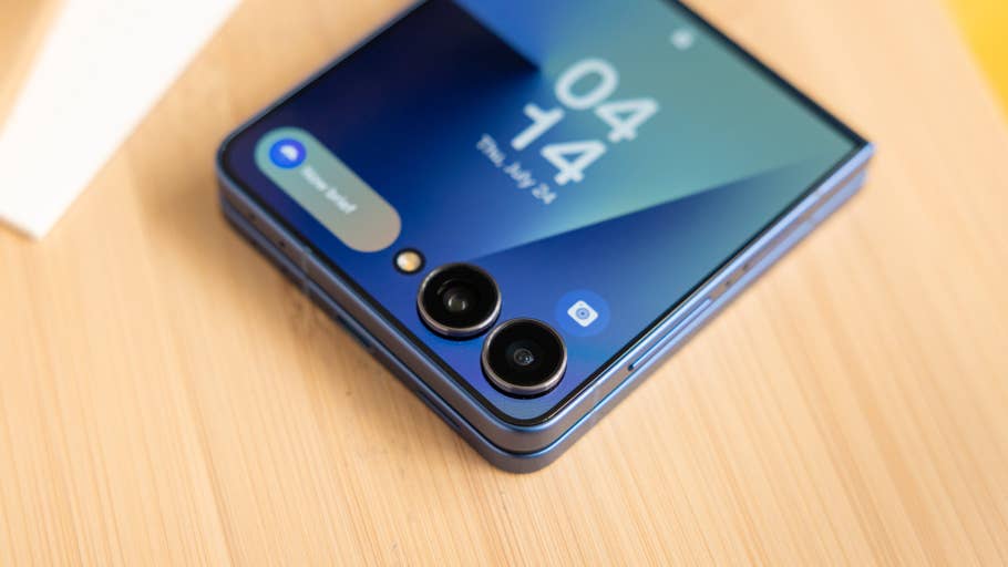 Samsung Galaxy Z Flip7 smartphone with dual cameras and a blue finish on a wooden surface.