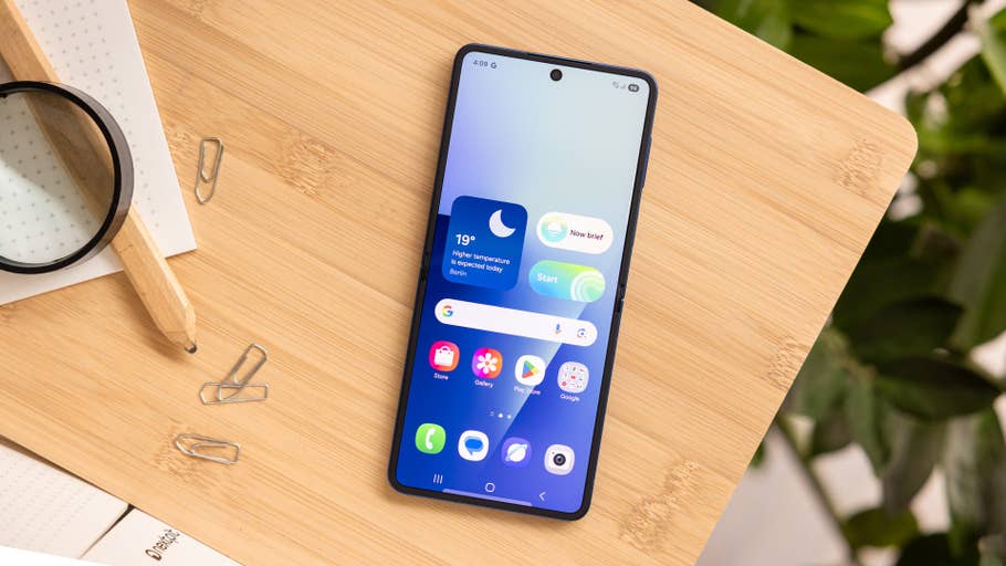 Samsung Galaxy Z Flip7 smartphone on a wooden surface with app icons displayed on the screen.