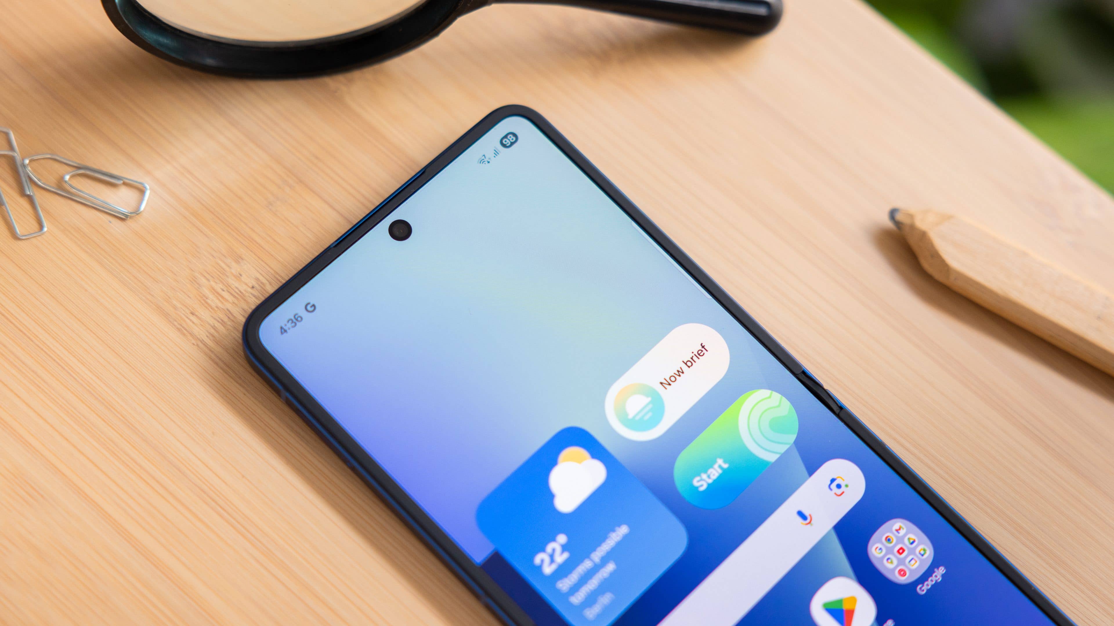 Samsung Galaxy Z Flip7 smartphone displaying a gradient wallpaper and app icons on a wooden surface.