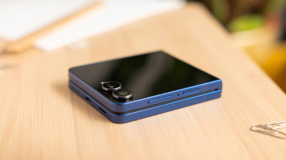 A Samsung Galaxy Z Flip7 smartphone in blue color, resting on a wooden surface.