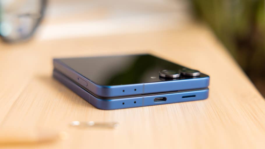 A blue Samsung Galaxy Z Flip7 smartphone lying flat on a wooden surface.