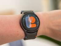 A person's wrist with a Samsung Galaxy Watch 7 displaying a colorful watch face.