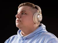 A person wearing Anker Soundcore Space One headphones, looking thoughtfully upwards against a dark background.