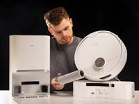 A man examines the SwitchBot S10 robotic vacuum and its docking station.