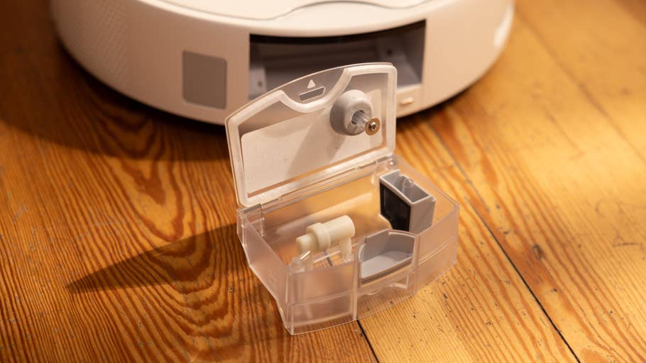 A SwitchBot S10 device with a transparent container showing off its components on a wooden surface.