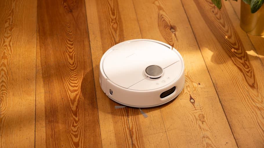 A white robot vacuum cleaner on a wooden floor.