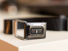 A black wearable device with a display showing 'WHOOP MG' lying on a flat surface.