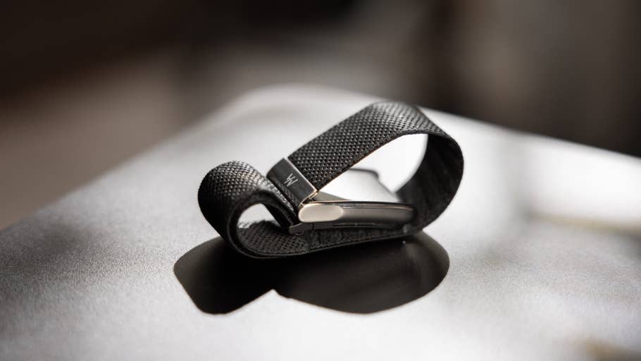 A black fabric strap folded over a metal clip on a dark surface.