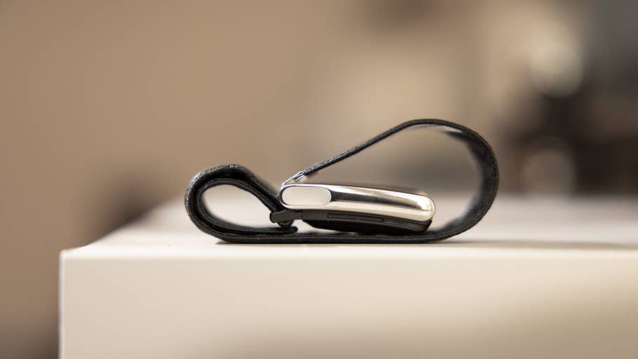 A sleek black strap holding a silver device, resting on a white surface.