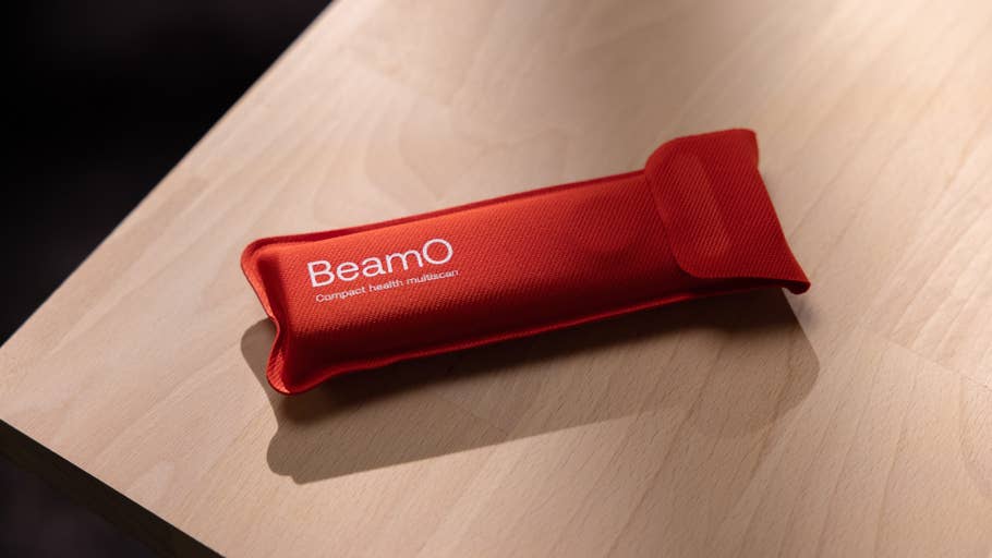 A red fabric pouch labeled u0027BeamO Compact health multiscanu0027 resting on a wooden surface.