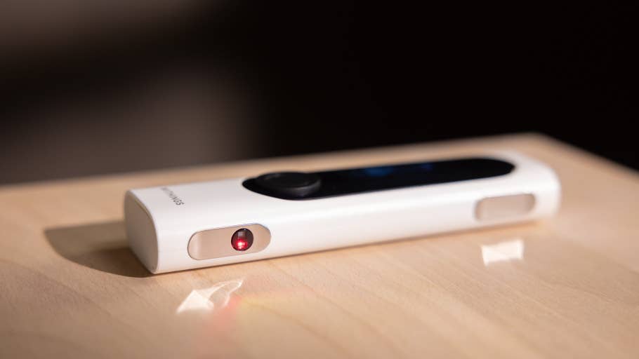 A Withings BeamO device on a wooden surface, featuring a red indicator light.