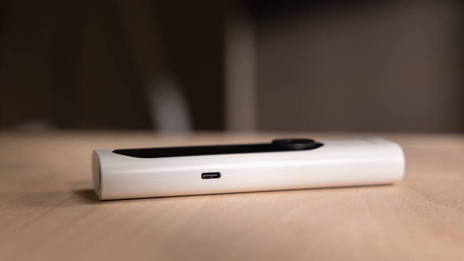 A white Withings BeamO device lying on a wooden surface, showcasing its USB-C port and sleek design.