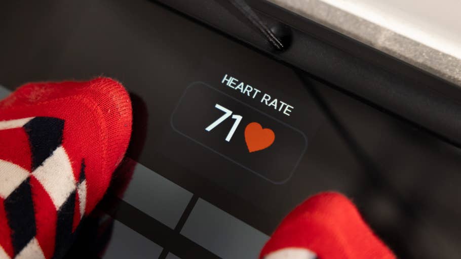 A personu0027s feet in patterned socks on a scale displaying a heart rate of 71.