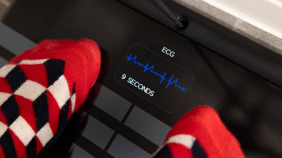 Feet in colorful socks on a digital scale displaying u0027ECGu0027 and u00279 SECONDSu0027.