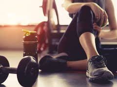 A woman sitting on the floor with a dumbbell and water bottle, focusing on fitness and health.