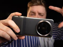 Xiaomi 14 Ultra seen from behind, held horizontally by a man standing in the background