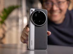 A person holding a Xiaomi 15 Ultra smartphone, smiling with greenery in the background.