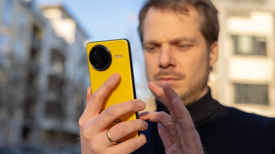 A man holds a yellow Poco F7 Ultra smartphone while outdoors.
