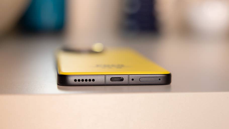 Close-up of a Poco F7 Ultra smartphone showing its bottom ports and yellow back.