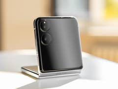 A Xiaomi Mix Flip smartphone standing on a table, showcasing its sleek design and dual camera setup.