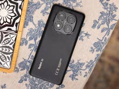 Black Xiaomi Redmi Note 14 Pro 5G smartphone on a floral-patterned tablecloth.