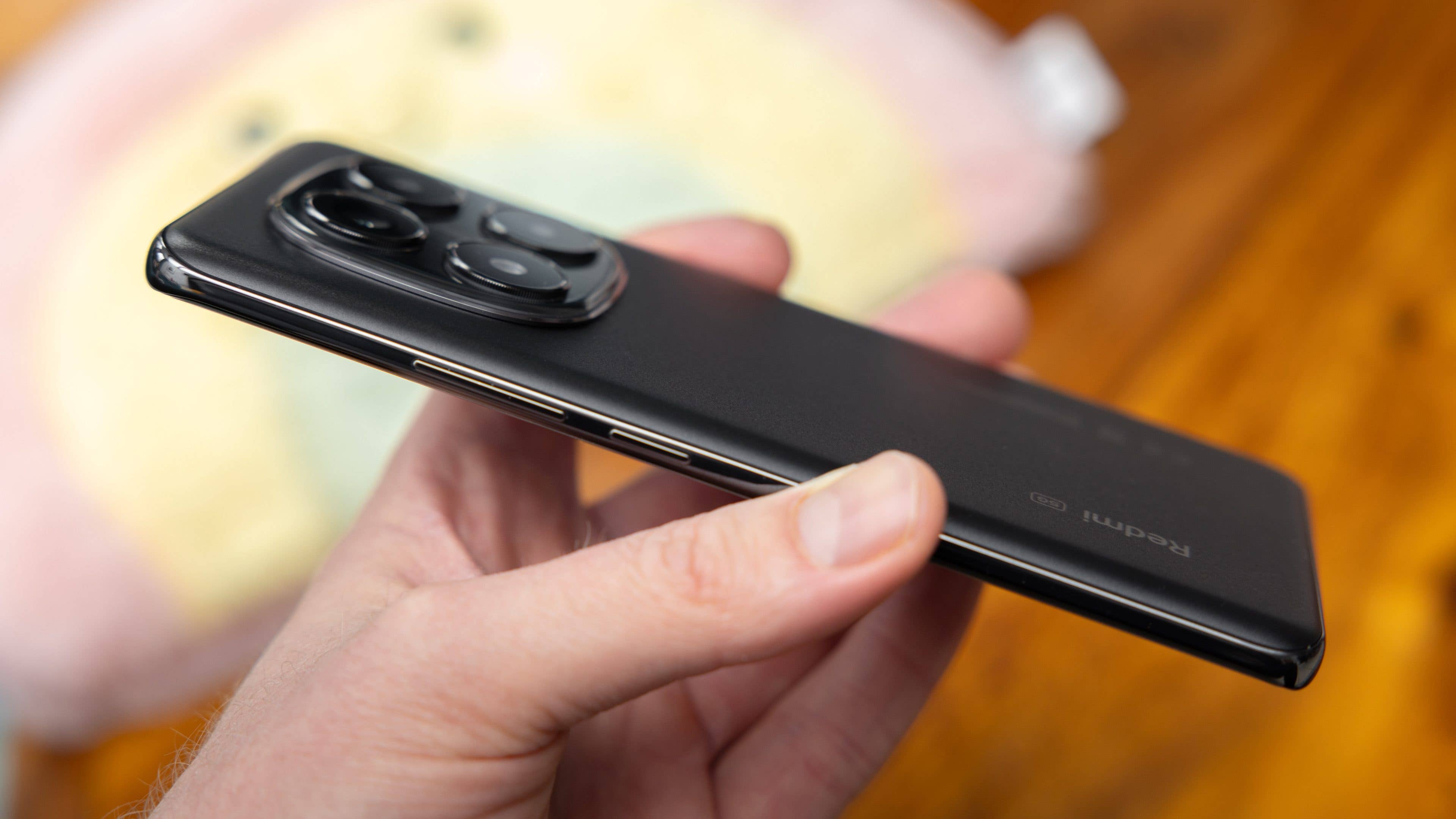 A person holding a Xiaomi Redmi Note 14 Pro 5G smartphone in black.