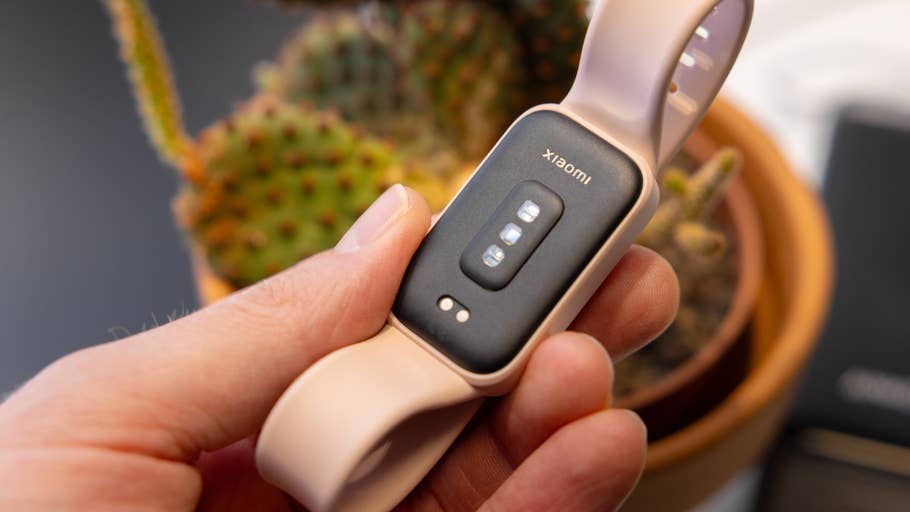 A person holding a Xiaomi Smart Band 9 Active, with a cactus in the background.