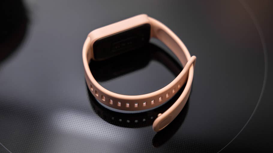 Xiaomi Smart Band 9 Active in soft pink on a black surface.