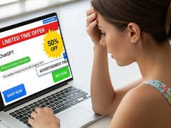 A woman looks stressed while using a laptop displaying a ChatGPT advertisement with a 50% off offer.
