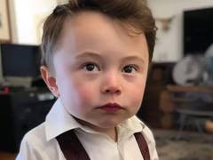 A young boy in a dress shirt with suspenders, looking thoughtfully at the camera.