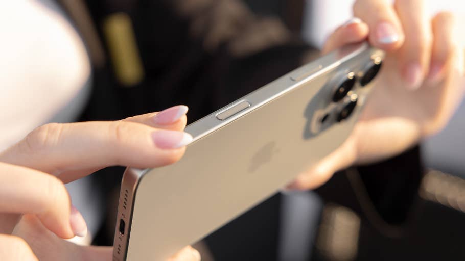 A person holds an iPhone 16 Pro and shows off the back and side buttons.