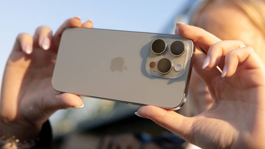 A person holding an iPhone 16 Pro with its cameras shown.